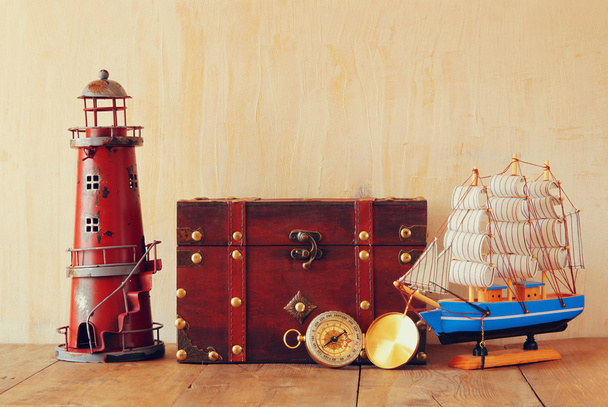 Античний компас, старовинний маяк, дерев'яний човен і старий комод на дерев'яному столі
 - Фото, зображення