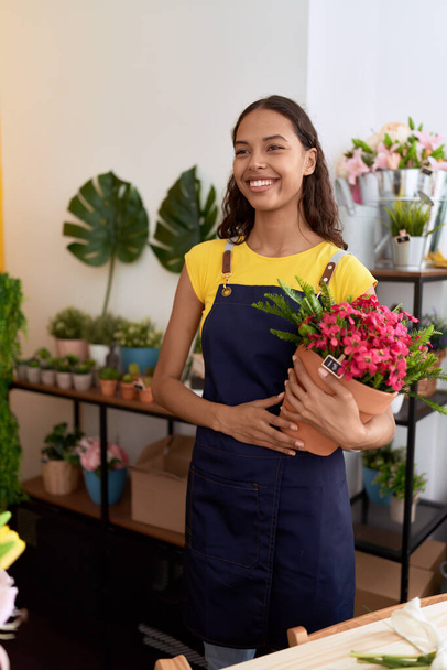 Young african american woman florist smiling confident holding plant at flower shop - Foto, Imagem