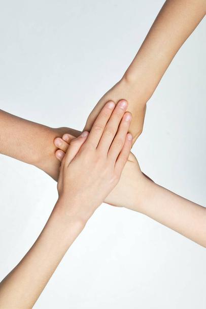 Крупним планом діти складають руки на сірому тлі. Друзі зі стопкою рук демонструють єдність і командну роботу. Поняття молоді, вираження, краса, емоції, жести. Реклама - Фото, зображення