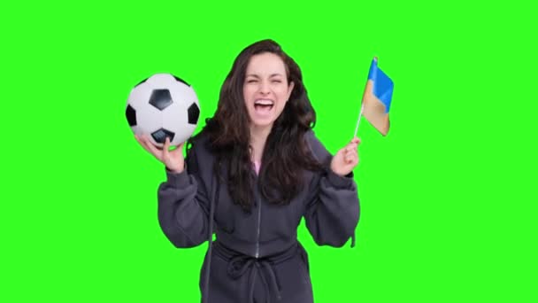 Boldog női rajongó ukrán zászló gazdaság egy focilabda, miközben ünneplő és sikoltozó cél zöld elszigetelt - Felvétel, videó