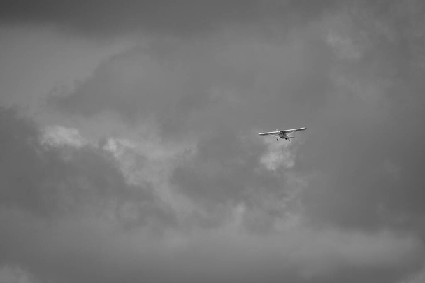 klein vliegtuig doet pirouettes in de bewolkte lucht - Foto, afbeelding
