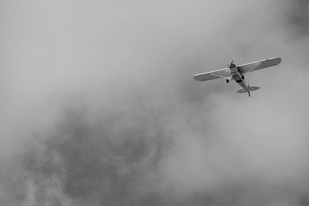 klein vliegtuig doet pirouettes in de bewolkte lucht - Foto, afbeelding