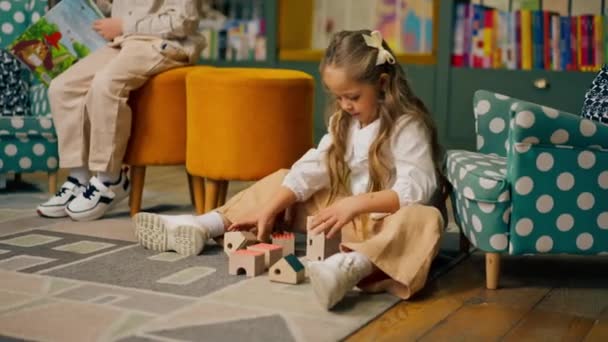 primo piano in una libreria nella zona dei bambini bella ragazza dai capelli lunghi gioca con giocattoli di legno - Filmati, video