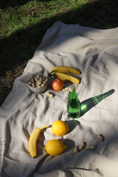 picnic. ocio. Hay nueces, manzanas, agua y plátanos en la alfombra de picnic para un aperitivo saludable. - Foto, imagen