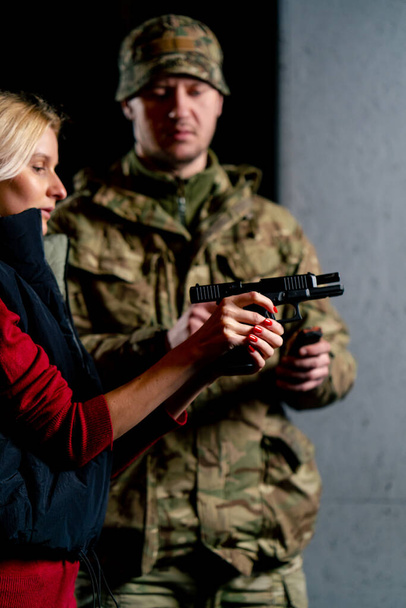in a professional shooting range a military man tells and shows a girl the correct stance with a pistol is - Photo, Image
