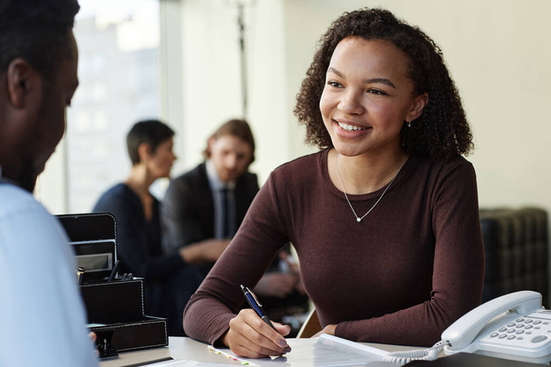 Портрет улыбающейся черной женщины, работающей с клиентом в юридической фирме - Фото, изображение
