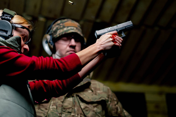 Na profesjonalnym strzelnicy wojskowy kontroluje technikę strzelania z pistoletu przy pierwszym strzale - Zdjęcie, obraz