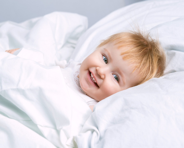 baby lying in a white bed - Foto, Imagen