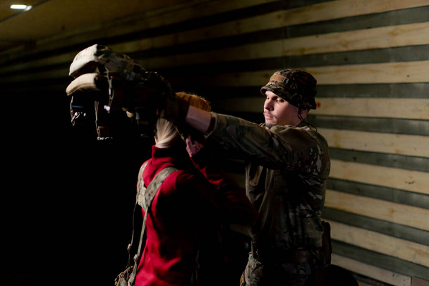 Em um campo de tiro profissional um treinador militar coloca munição tática em uma garota barata - Foto, Imagem