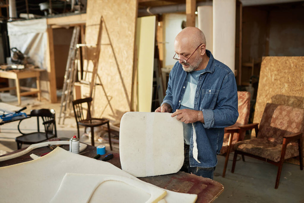 Portrét zkušeného staršího řemeslníka pracujícího na rekonstrukci nábytku v dílně, kopírovací prostor - Fotografie, Obrázek