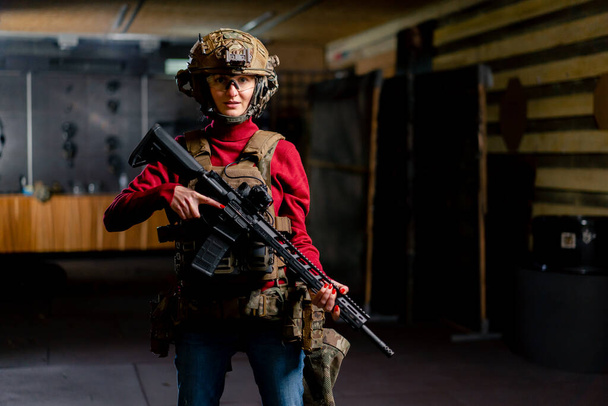 プロの射撃範囲で 戦術弾の女の子がNATOライフルで立っています - 写真・画像