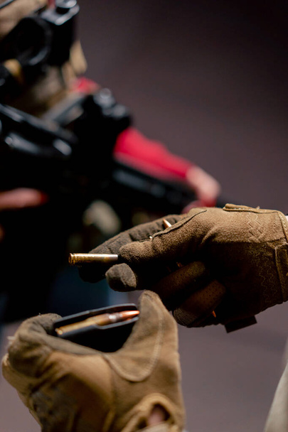 close-up in een professionele schietbaan een militair rust een magazijn uit met patronen - Foto, afbeelding