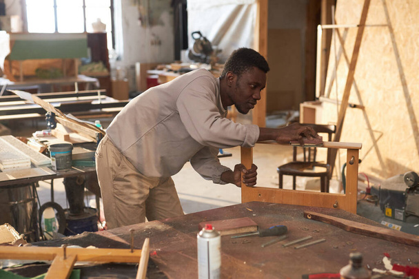 カーペントリーワークショップ,コピースペースで木製家具を建てる若い黒人男性の側面の肖像画 - 写真・画像