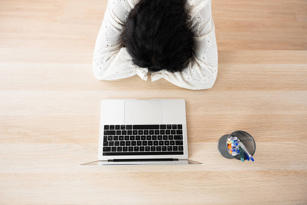 Draufsicht auf eine müde Person vor dem Laptop. Konzept für Kleinunternehmen und Startschwierigkeiten - Foto, Bild