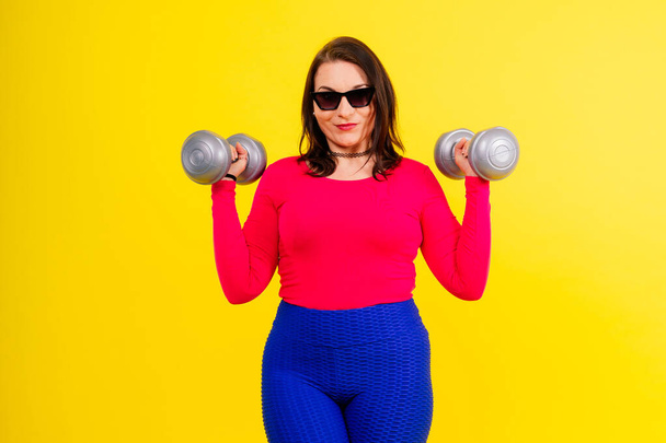 Deportiva mujer regordeta haciendo ejercicios con pesas. Motivación deportiva y estilo de vida saludable - Foto, imagen