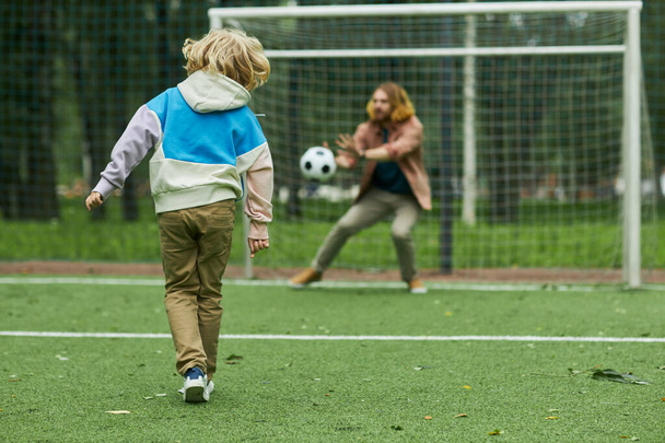 Vista trasera del niño jugando al fútbol con el padre y anotando gol, espacio para copiar - Foto, Imagen