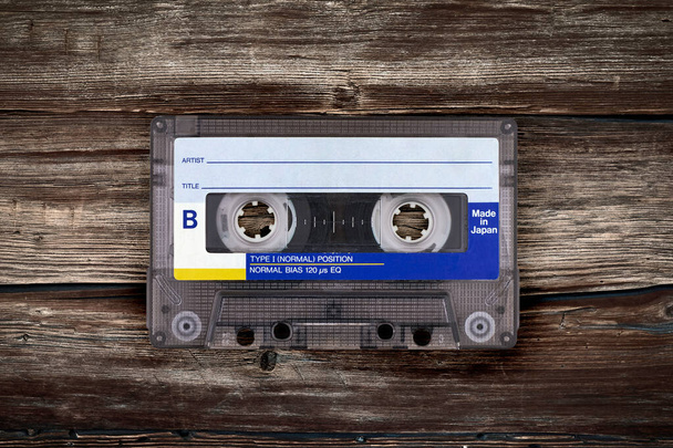 Retro cassette tape on a textured brown wooden surface. - Photo, Image