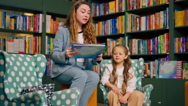 in einer Buchhandlung im Kinderbereich schöne Mädchen und Jungen wollen nicht, dass ihre Mutter ihnen ein Buch vorliest - Filmmaterial, Video
