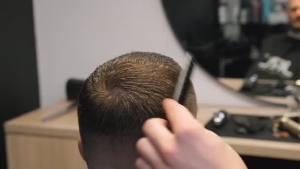 Coiffeur peina el pelo corto mojado del hombre por el espejo en el primer plano de la peluquería. Peluquería hace corte de pelo masculino a cabello masculino en salón de belleza - Metraje, vídeo