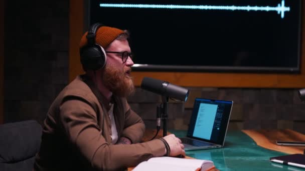 Podcaster masculin interviewant un invité dans un studio d'enregistrement. Barbu gars assis à la table avec ordinateur portable et microphone - Séquence, vidéo