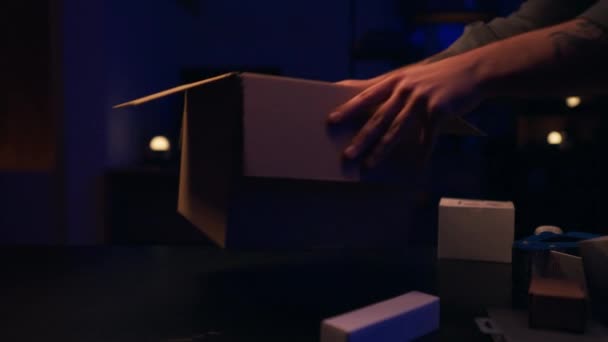 Una persona abriendo una caja en una habitación con poca luz. - Metraje, vídeo