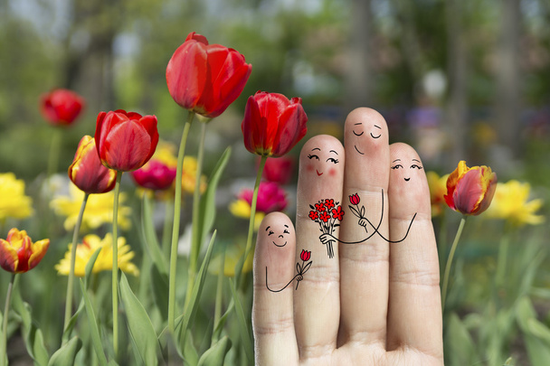 konzeptionelle Familienfingerkunst. Vater, Sohn und Tochter schenken ihrer Mutter Blumen. - Foto, Bild