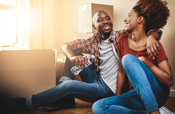 Black couple, real estate and hug on floor of new house with bonding, support and break or relax from moving. People, homeowner or excited for property investment, dream home or relocation with boxes. - Photo, Image