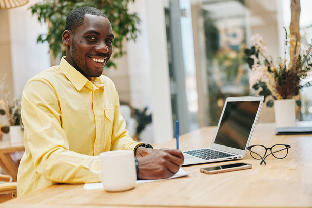 Glücklicher Mann afrikanischer Geschäftsmann sitzt Lächeln Arbeit Lebensstil Erwachsene moderne Technologie suchen Computer jung Tisch mit Business schwarz männlich Laptop Person - Foto, Bild