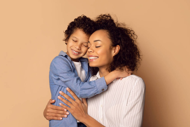 Afro-Amerikaanse vrouw houdt een kind in haar armen, toont moederlijke zorg en genegenheid in een hartverwarmend moment. - Foto, afbeelding