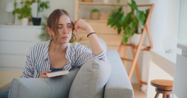 Eine traurige Frau sitzt auf dem Sofa, ihr Gesichtsausdruck vermittelt Unzufriedenheit und Trauer, während sie mit ihren Gefühlen ringt - Filmmaterial, Video