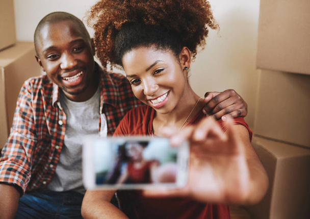 Schwarzes Paar, Selfie und Lächeln auf dem Boden mit Boxen für ein neues Haus, Bindung oder Auszeit vom Umzug mit der Erinnerung. Menschen, Hausbesitzer und begeistert für Immobilieninvestitionen, Traumhaus oder Profilbild-Update. - Foto, Bild