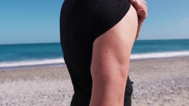 Χέρι ενός τύπου Triceps στην παραλία κοντά στον ωκεανό. - Πλάνα, βίντεο