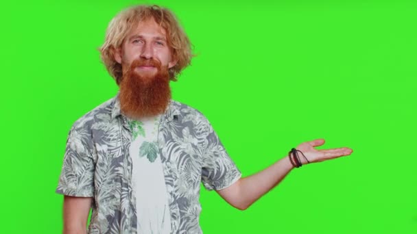 Young bearded man showing thumbs up and pointing right empty place, advertising area for commercial text copy space for goods promotion advertisement. Guy isolated on chroma key background. Lifestyles - Footage, Video