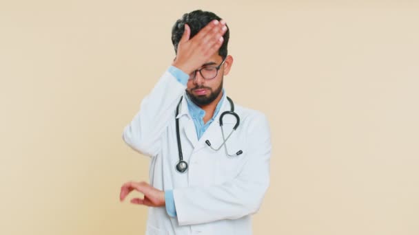 Παλάμη προσώπου. Ντροπή σου. Αναστατωμένη λυπημένος Ινδός καρδιολόγος νεαρός γιατρός κάνει χειρονομία πρόσωπο παλάμη, αίσθημα βαρεμάρας,, απογοητευμένος από το αποτέλεσμα, άσχημα νέα. Αραβικός φαρμακοποιός φαρμακοποιός τύπος σε μπεζ φόντο - Πλάνα, βίντεο