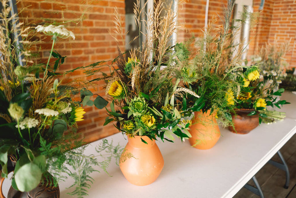 Élégantes pièces maîtresses de fleurs sauvages ornant une table festive à un événement intérieur d'une longue table - Photo, image