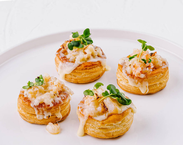 Drei köstliche Garnelen vol-au-vents garniert mit Kräutern auf einem weißen Teller, perfekt für elegante Vorspeisen - Foto, Bild