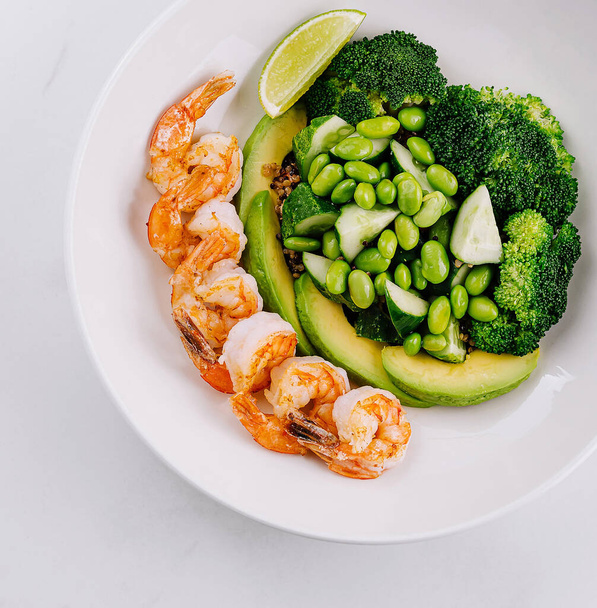 Ensalada verde fresca con camarones, brócoli, aguacate y lima sobre un fondo blanco - Foto, imagen