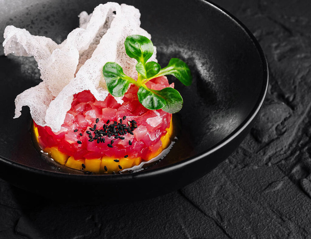 Elegancka prezentacja tatara z tuńczyka zwieńczona nasionami sezamu i ziołami, podawana z chrupiącym chlebem - Zdjęcie, obraz
