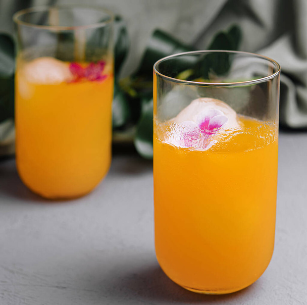 Eleganti bevande arancioni con fiori commestibili in ghiaccio, perfette per eventi estivi - Foto, immagini