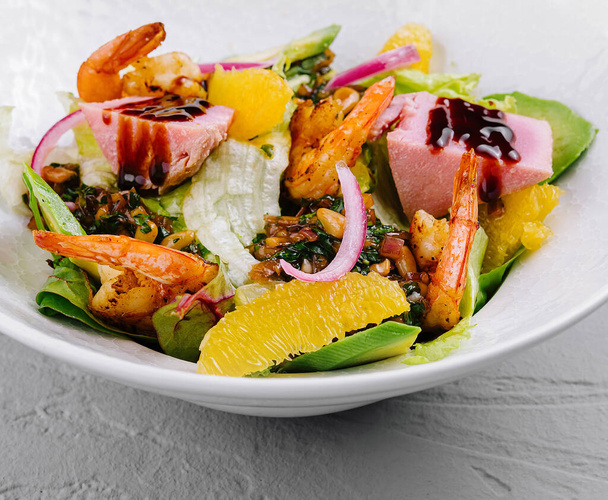 Pulzující miska salátu z mořských plodů se šťavnatými krevetami a citrusovými segmenty na zeleném lůžku - Fotografie, Obrázek