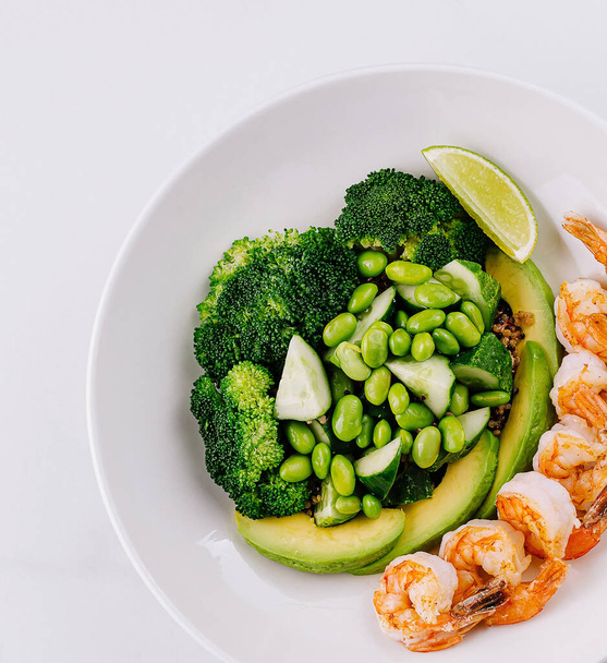 Fresh green salad with shrimp, broccoli, avocado, and lime on a white background - Photo, Image