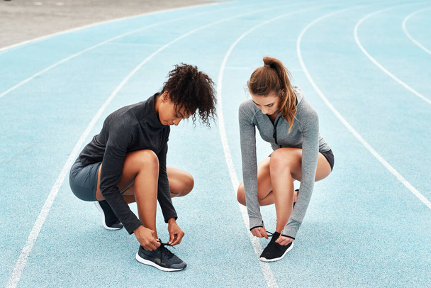 Sports, women and race track in sportswear for training, outdoor or workout in stadium for wellness. Female athletes, shoes and break in exercise for tournament, competition or contest as runners. - Photo, Image