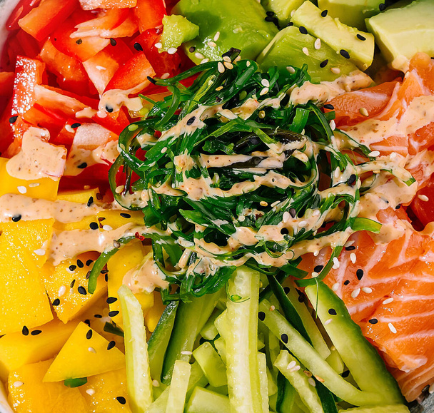 Bovenaanzicht van een kleurrijke zalmpot met verse groenten en rijst close-up - Foto, afbeelding