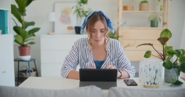 Μια γυναίκα μελετά προσεκτικά online μαθήματα χρησιμοποιώντας το ψηφιακό tablet της από την άνεση του σπιτιού, συμμετέχοντας σε e-learning - Πλάνα, βίντεο