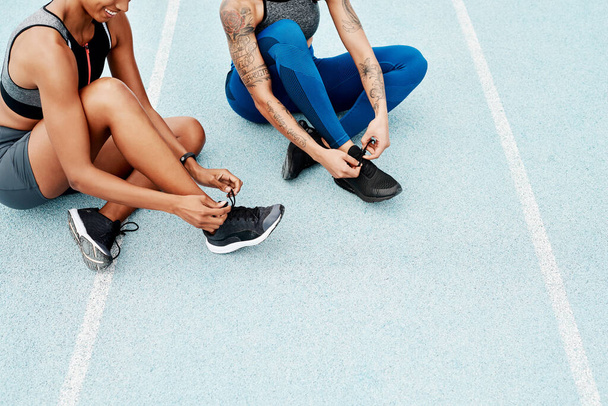 Hände, Menschen oder Sportler schnüren Schuhe für Leichtathletik, Training oder Outdoor-Fitnesstraining im Stadion. Teamwork, Beine und Läufer mit Sportschuhen bereit zum Joggen und Walken für das Wohlbefinden. - Foto, Bild