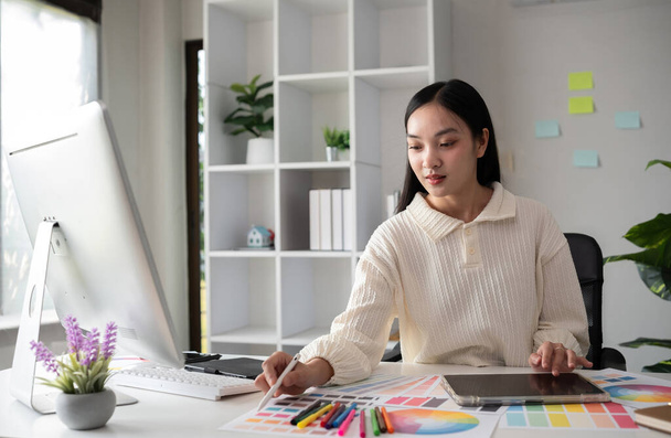 Naissuunnittelija työskentelee graafisessa suunnittelussa tietokoneella Istu ja valitse värit ja toimi intensiivisesti toimistossasi.. - Valokuva, kuva