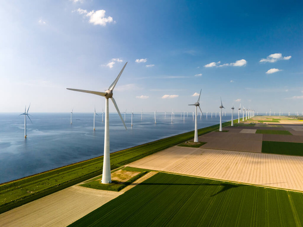 Klidná větrná farma ve Flevolandu, Nizozemsko. Řady majestátních větrných mlýnů půvabně se otáčející v harmonii, využívající sílu větru k výrobě obnovitelné energie. - Fotografie, Obrázek