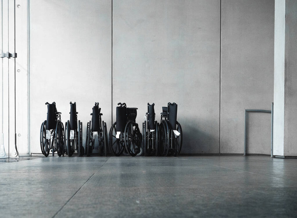 Silla de ruedas en el edificio. Equipo de transporte para discapacitados de pie en la habitación con fondo de hormigón. - Foto, Imagen