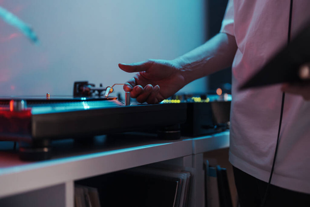 Primo piano di una mano di DJ su un giradischi, che suona musica a una festa vibrante. - Foto, immagini
