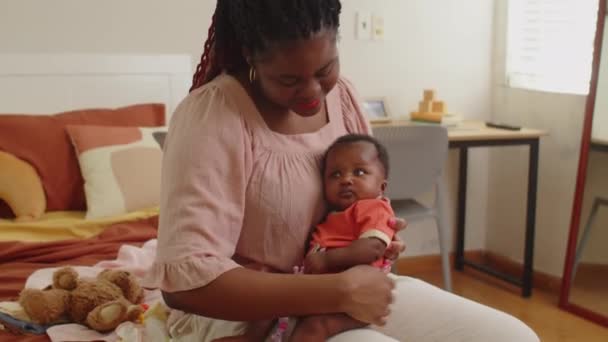 Tilt down shot van jonge zwarte moeder houden haar baby meisje terwijl het doorbrengen van tijd samen thuis - Video
